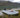 A dog riding on a white inflatable catamaran boat by the lake