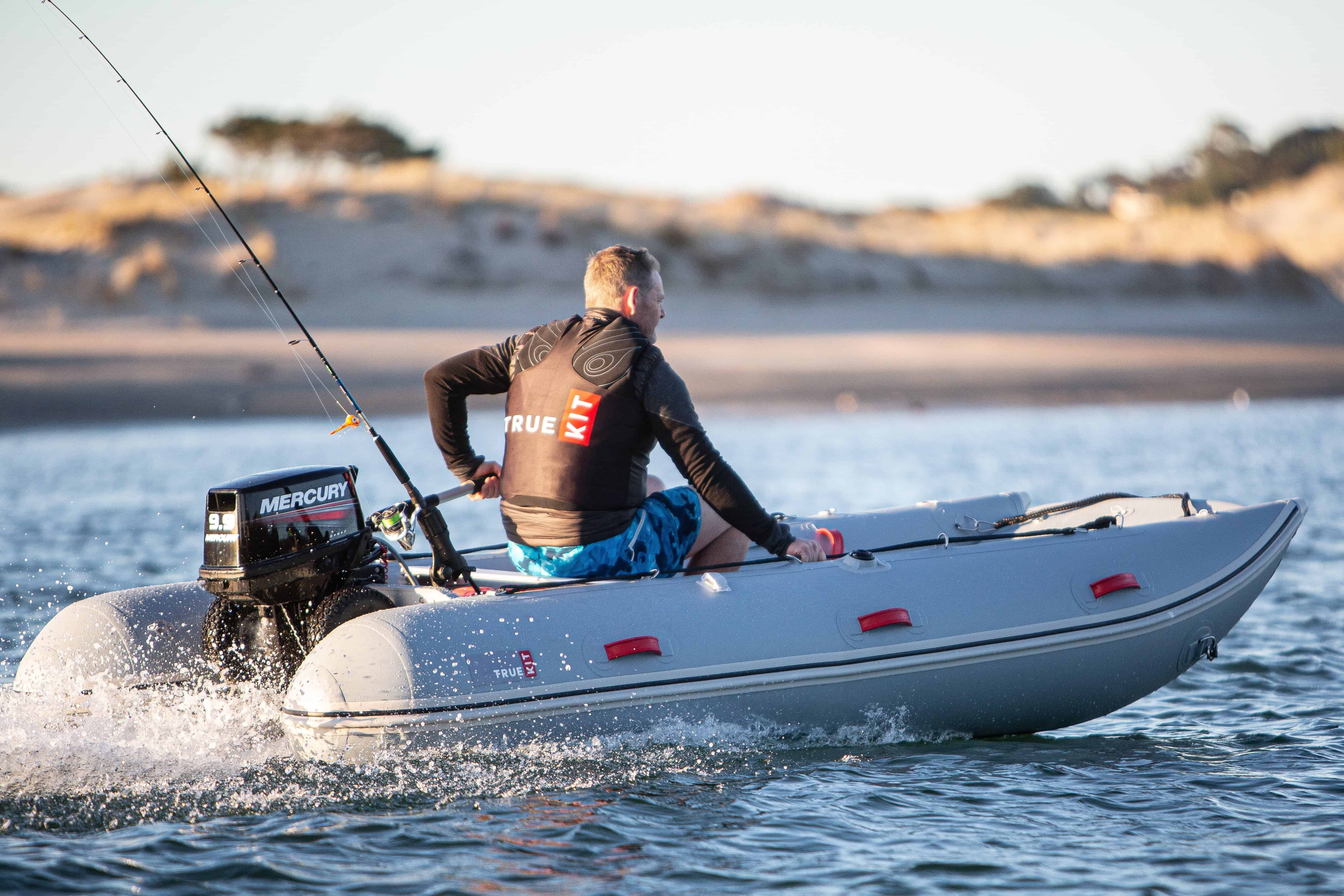 a man wearing a true kit life vest riding on inflatable catamaran boat