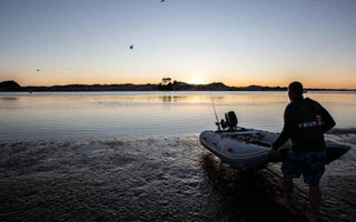 At sunrise, a man launching his inflatable boat to sail
