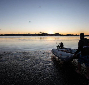 At sunrise, a man launching his inflatable boat to sail