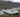 A dog riding on a white inflatable catamaran boat by the lake